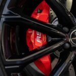 Detailed view of a sports car wheel highlighting the red brake caliper and sleek design.