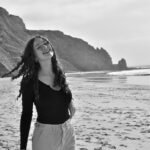 A woman laughs freely on a scenic summer beach in Faro District, Portugal.