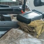 Close-up of car diagnostics tool on engine in a garage setting.